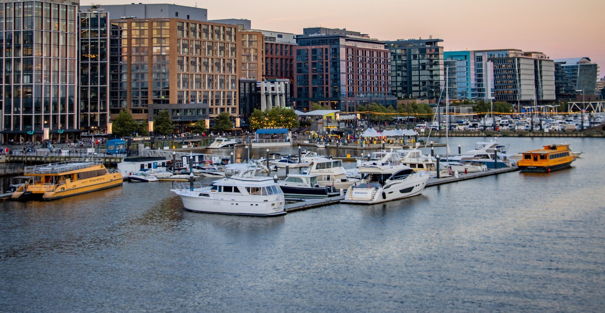 A bustling waterfront scene with restaurants and people enjoying the atmosphere at The Wharf in Washington D.C. 